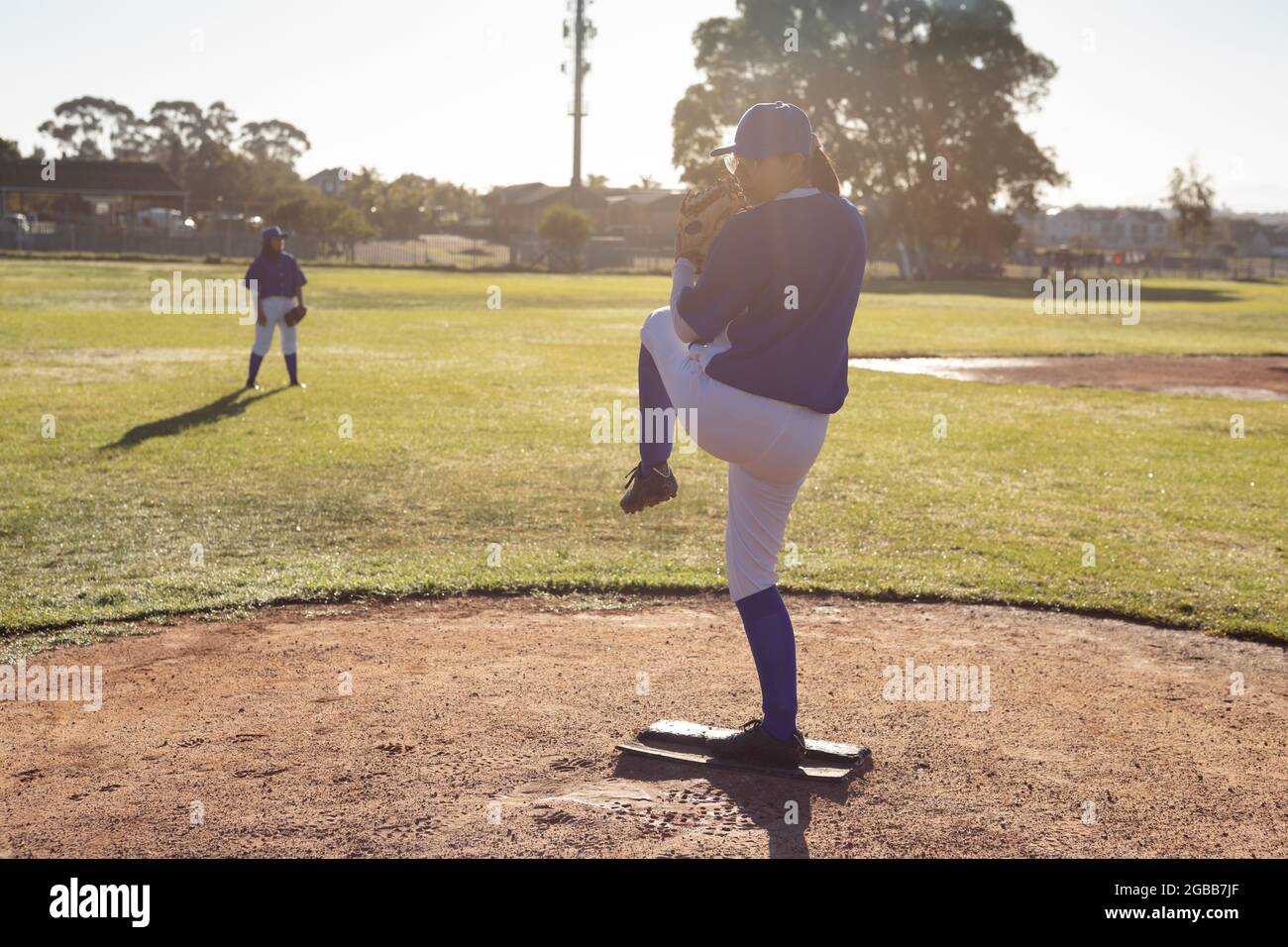Mixed race female baseball pitcher on sunny baseball field preparing to