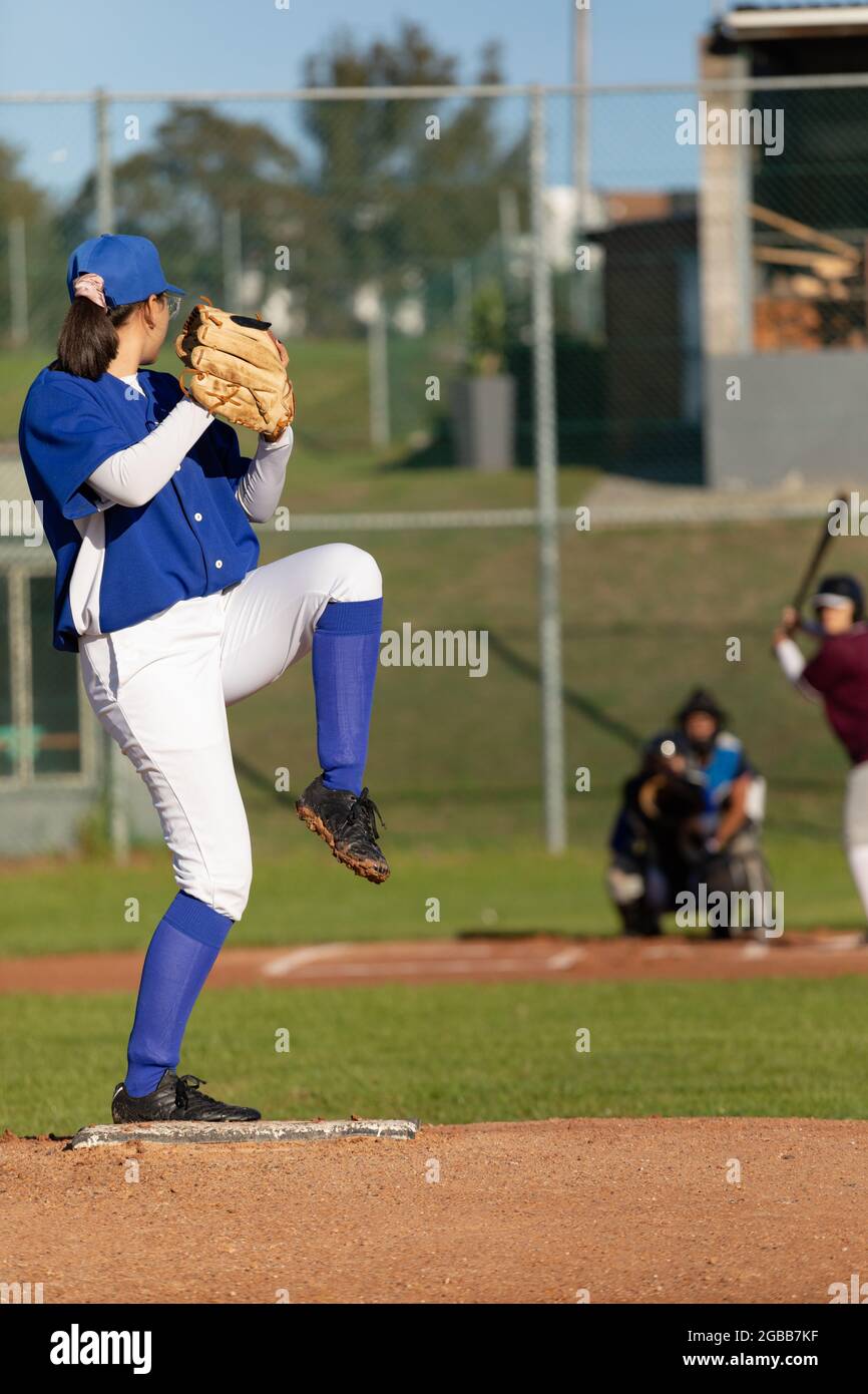 Mixed race female baseball pitcher on sunny baseball field preparing to