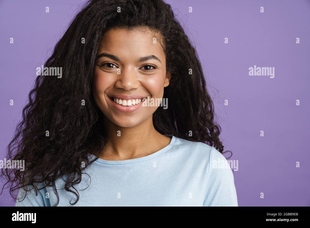 Young black woman with curly hair smiling and looking at camera ...