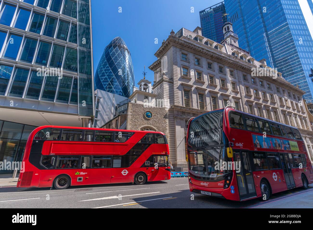 View of The Gherkin peaking between other contemporary architecture and red buses, City of London, London, England, United Kingdom, Europe Stock Photo