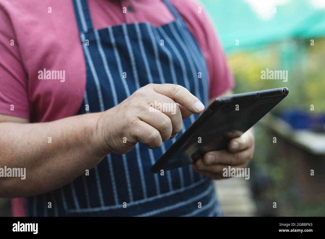 Hands of caucasian male gardener using tablet at garden centre Stock Photo