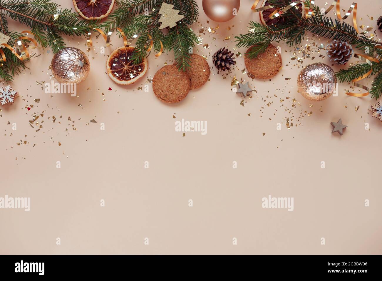 Christmas festive background. Christmas tree branches, balls, cookies and golden confetti on beige background. Top view, flat lay, copy space. Stock Photo