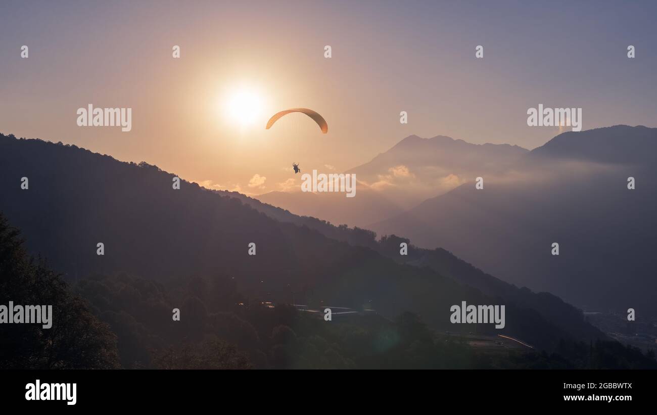 Yellow Paraglider at Sunset Clear Sky over a Wide Valley between Mountain Ranges, Extreme Tourism, Adventure, Fresh Mountain Air, Unforgettable Impres Stock Photo