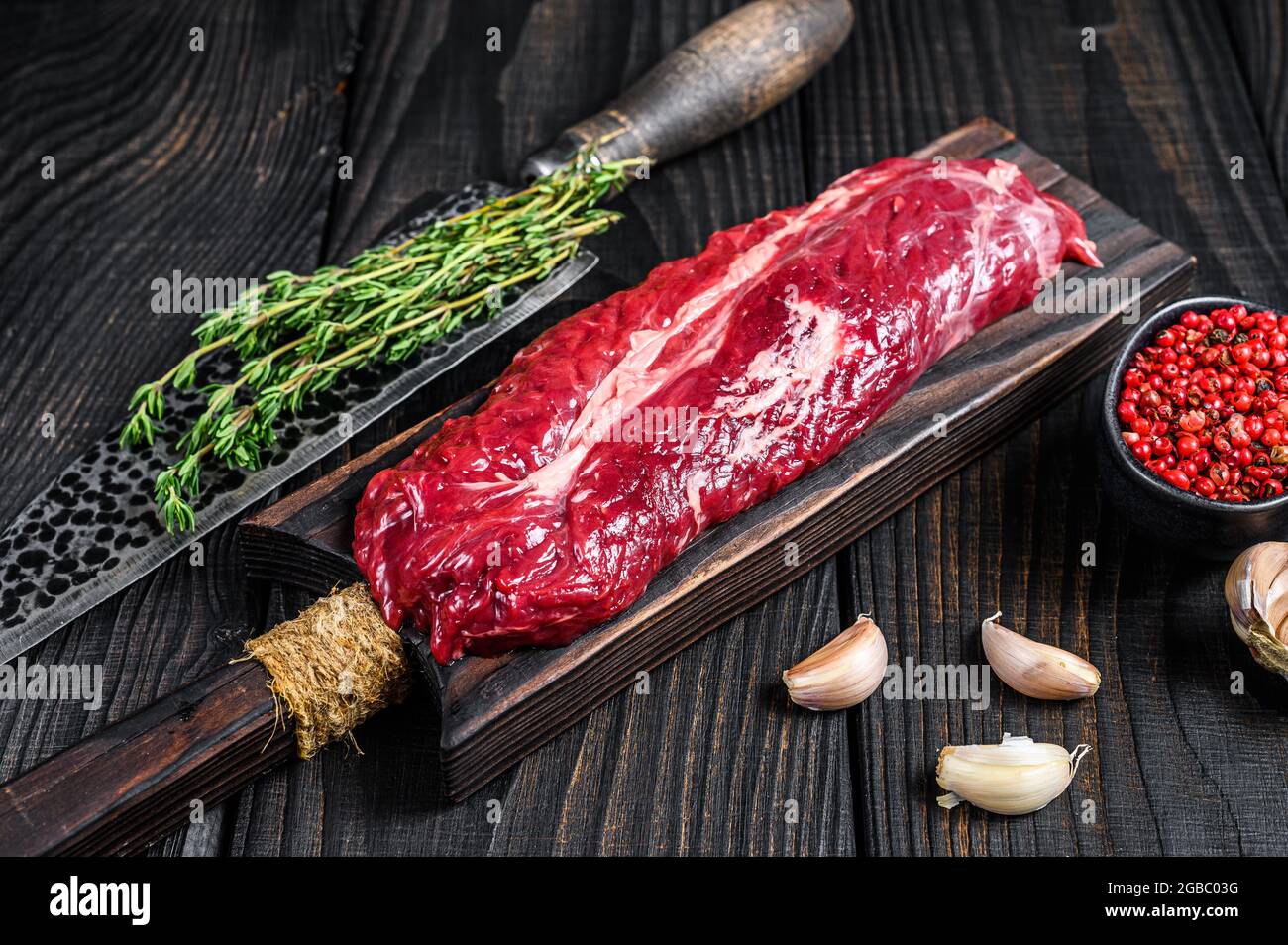 Raw Onglet Hanging Tender beef meat steak on a wooden cutting board. Black wooden background. Top view Stock Photo