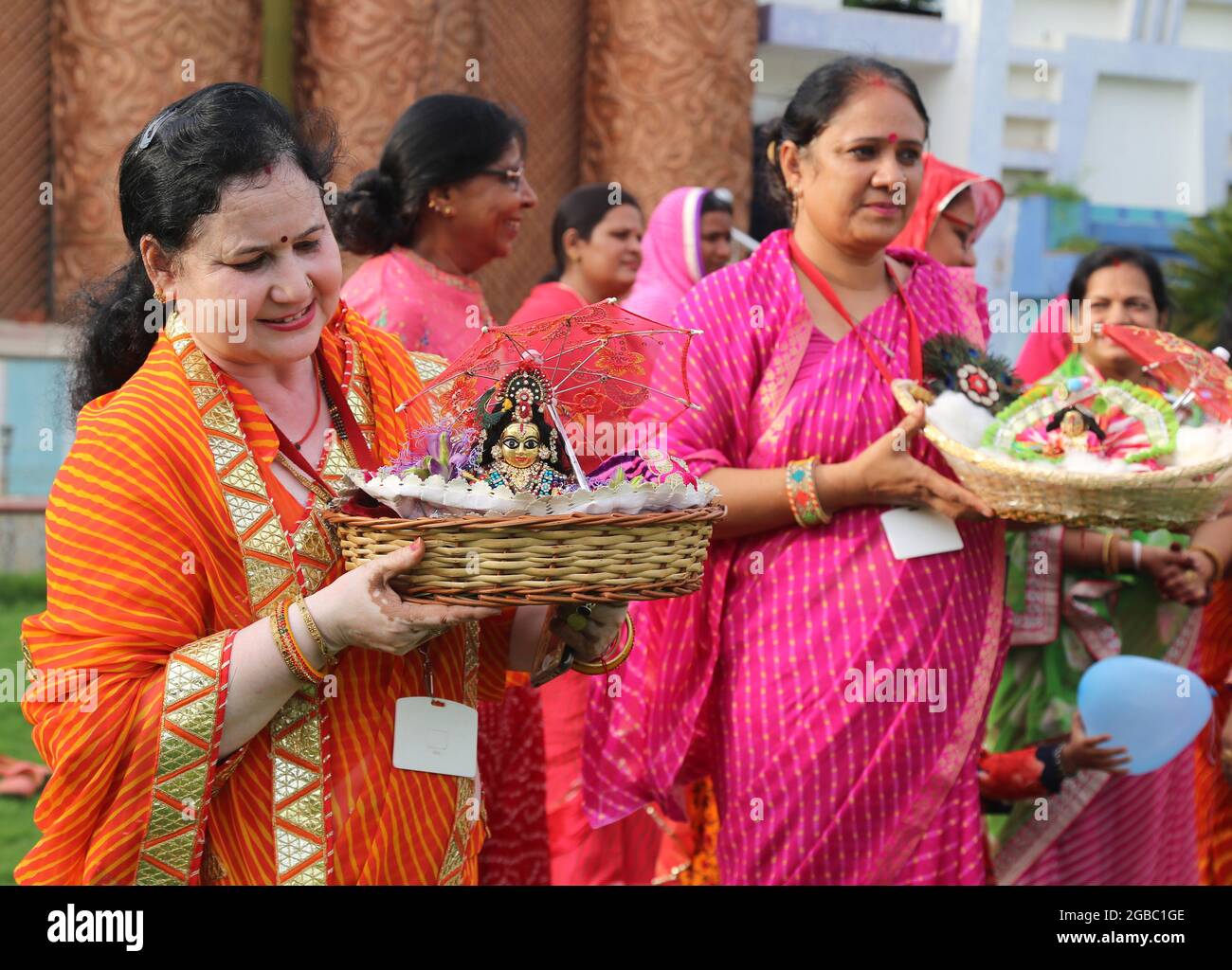 Beawar, Rajasthan, India, August 2, 2021: Hindu women wearing colorful lahariya saree, carrying the idols of Laddu Gopal (Lord Krishna) as they celebrate the holy month of Sawan (Shravan) in Beawar. Photo: Sumit Saraswat Stock Photo