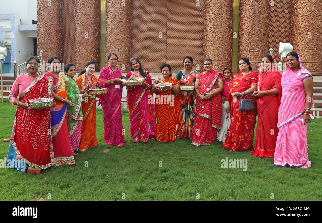 Beawar, Rajasthan, India, August 2, 2021: Hindu women wearing colorful lahariya saree, pose for a picture with the idols of Laddu Gopal (Lord Krishna) as they celebrate the holy month of Sawan (Shravan) in Beawar. Photo: Sumit Saraswat Stock Photo
