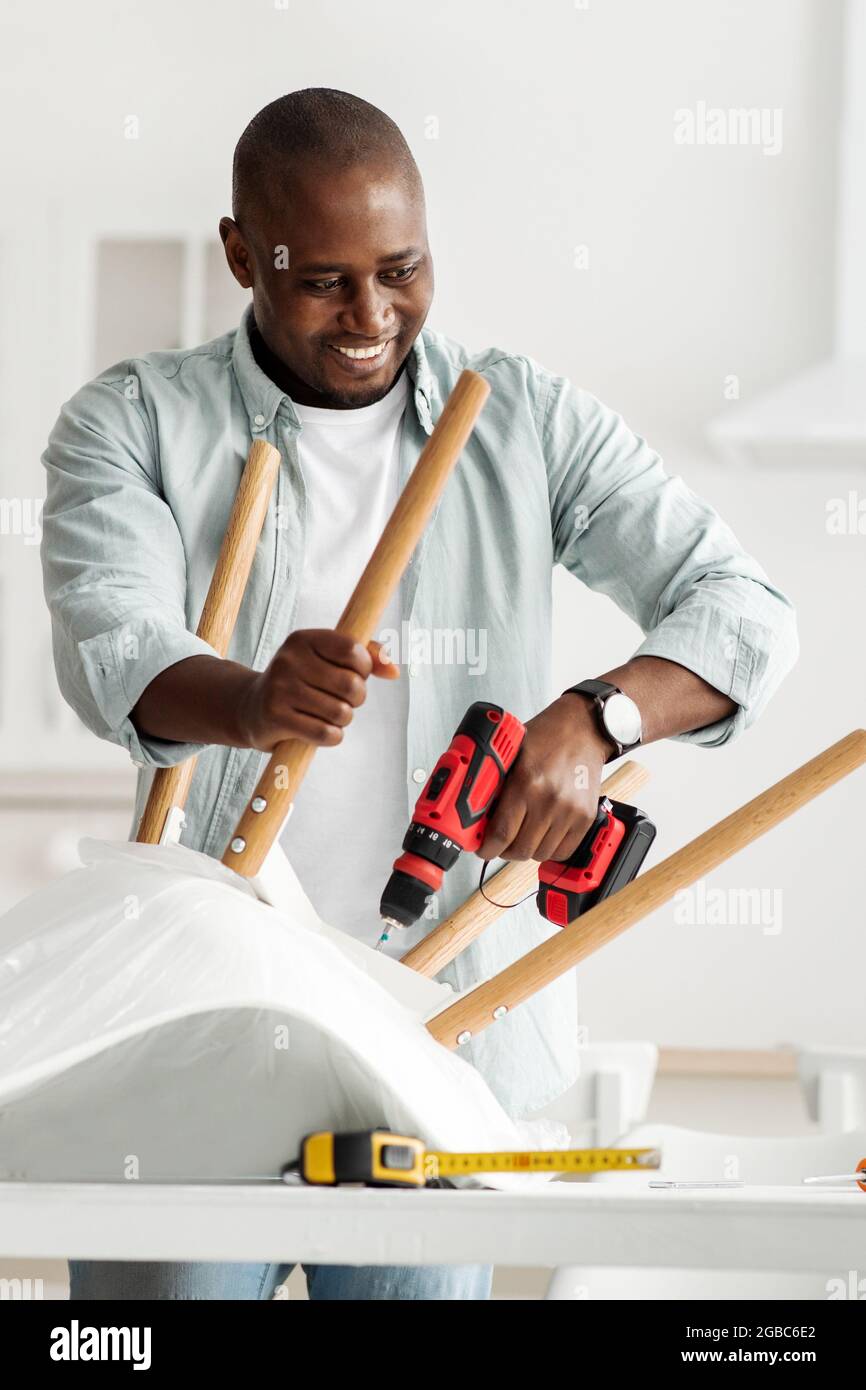 Manual job at home. Happy millennial black man assembling furniture