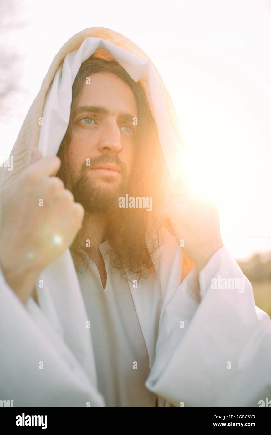 Portrait of Jesus Christ standing in meadow clothed in his traditional white  robe against sunset background Stock Photo - Alamy