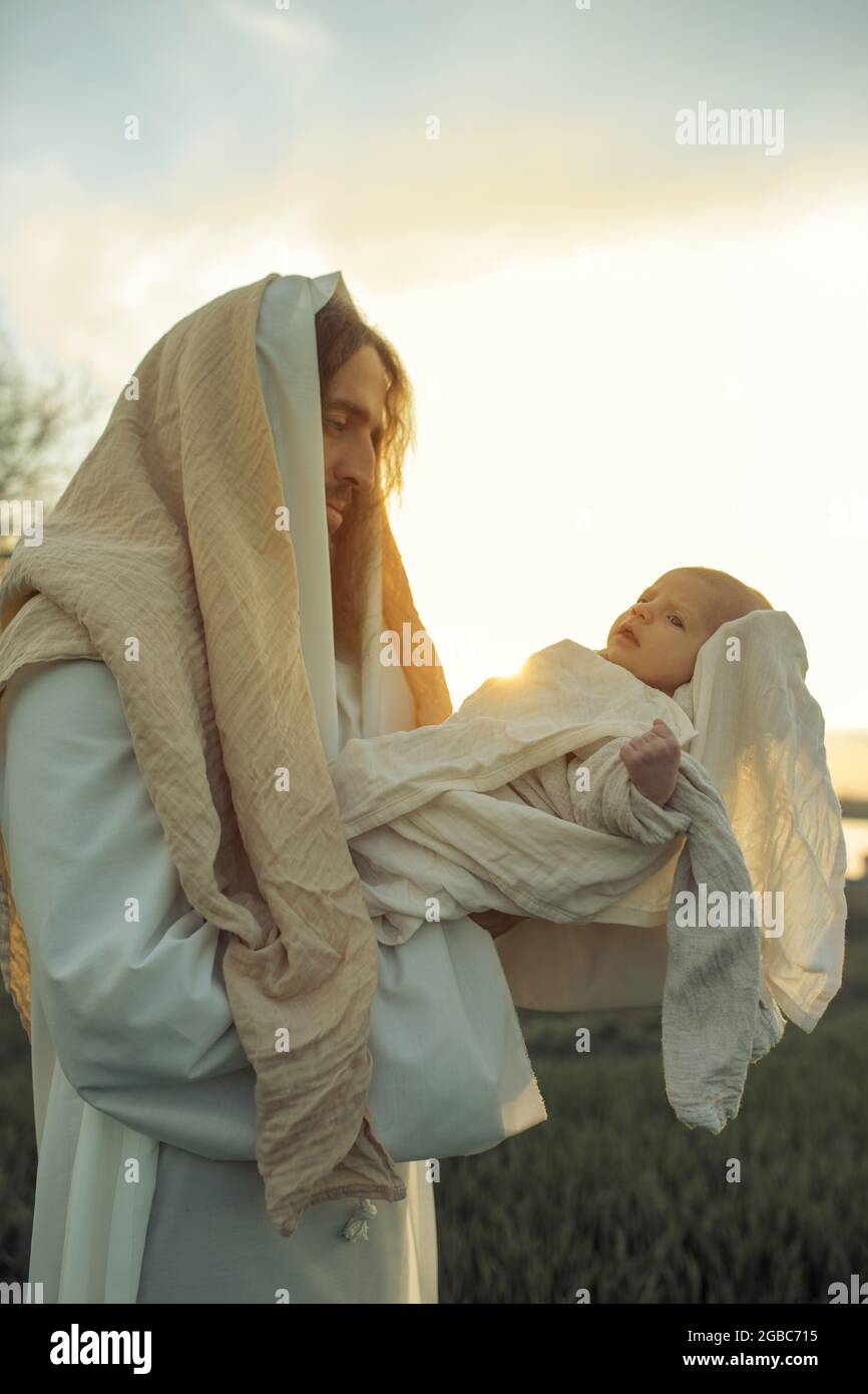 Saint Joseph holds baby Jesus in his arms and looks to him with love
