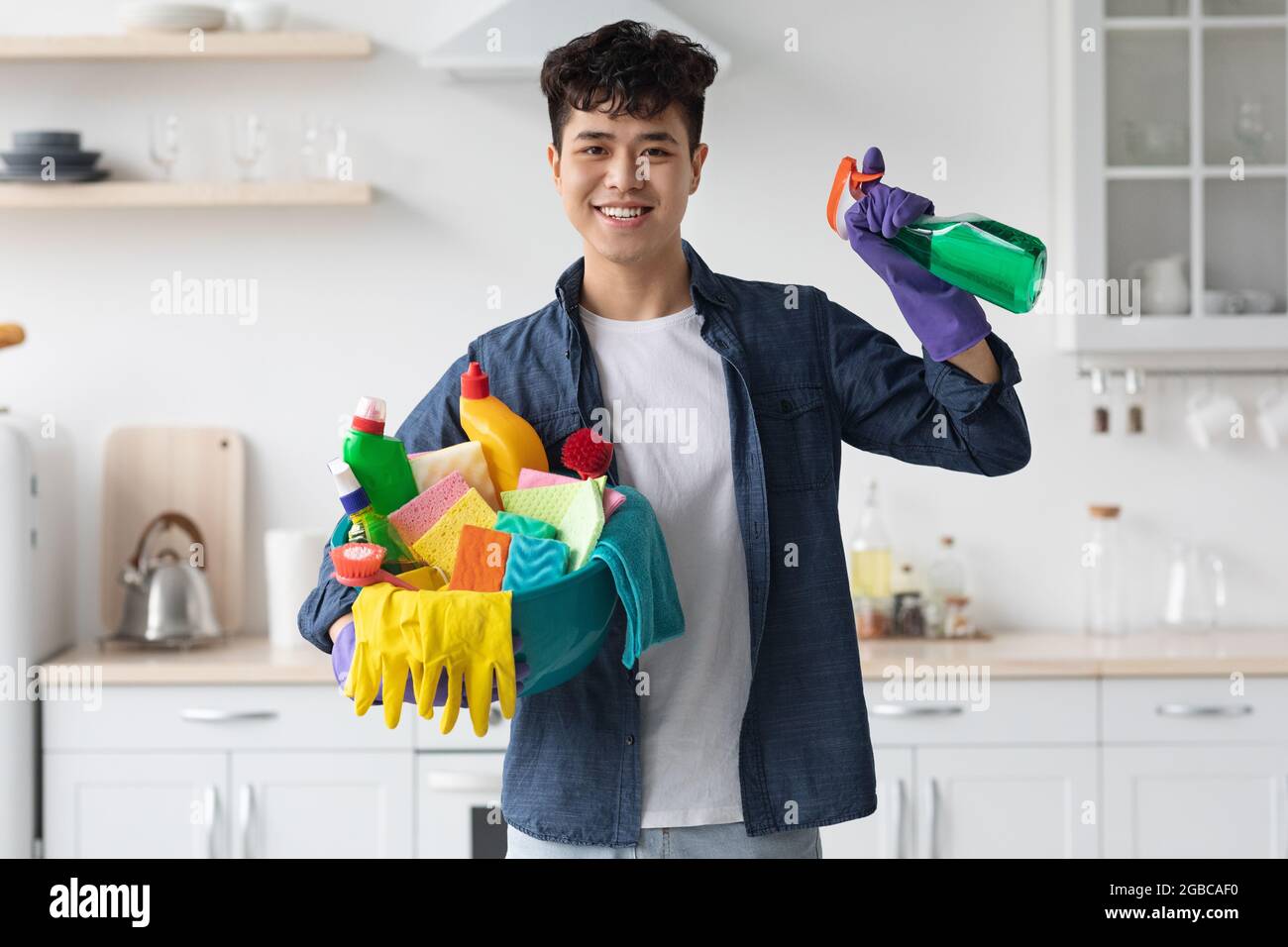 Smiling asian man housekeeper cleaning apartment, copy space Stock