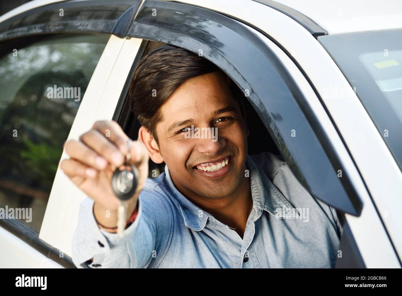 happy Indian man showing car key from car Stock Photo