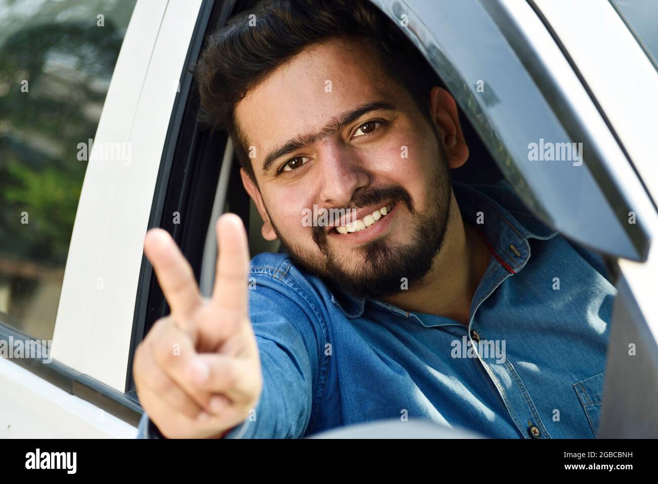 Indian driver showing victory sign from car, car loan concept Stock Photo