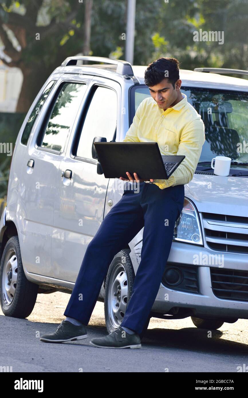 Indian man looking on laptop for mechanic on road or vehicle due to puncture car Stock Photo