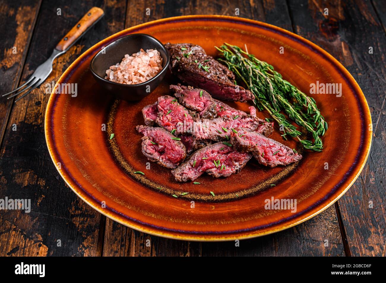 Medium rare Sliced grilled Onglet Hanging Tender meat beef steak on a plate. Dark wooden background. Top view Stock Photo