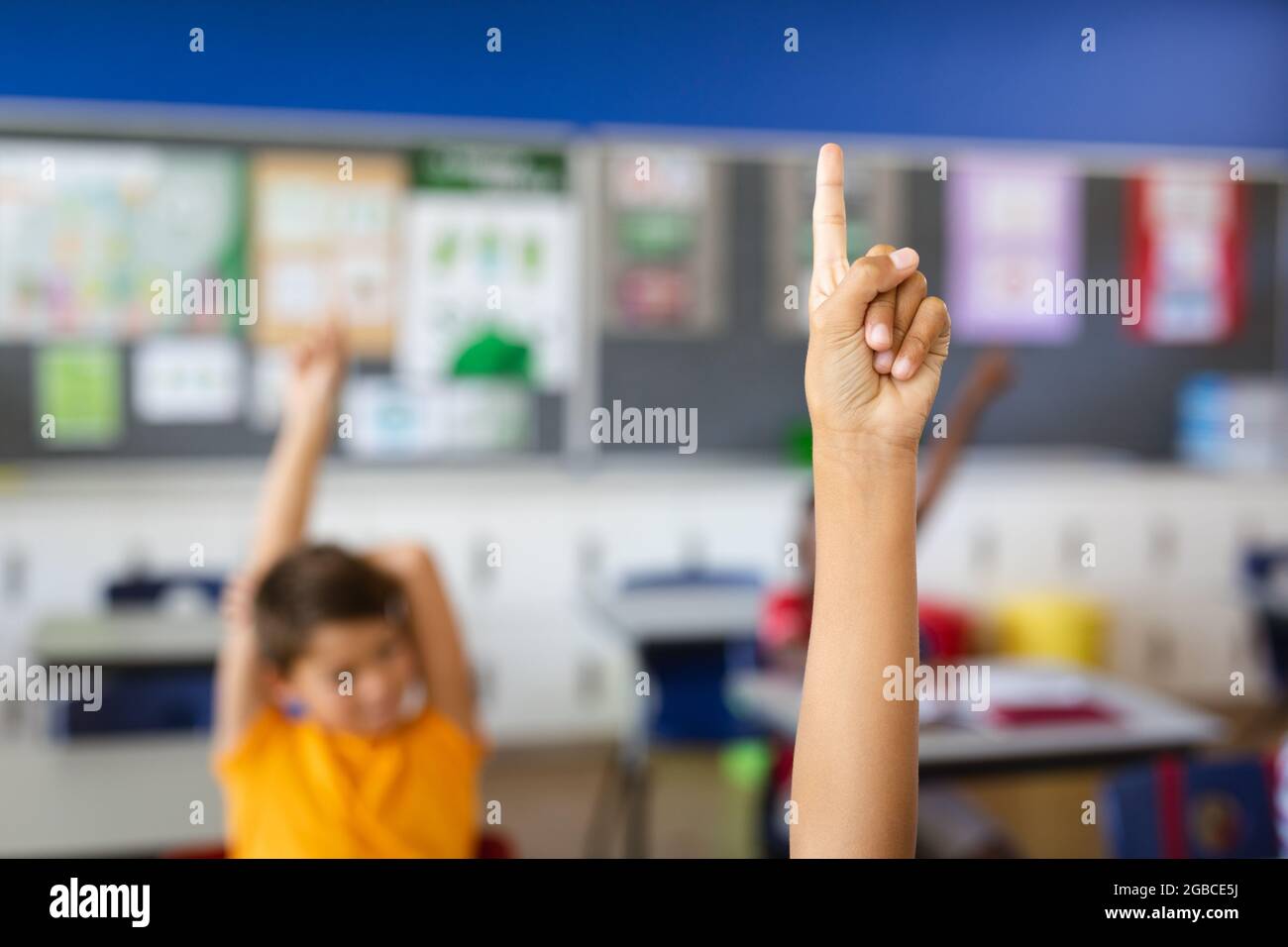 Boy raising his hand for participation in the class at elementary school Stock Photo