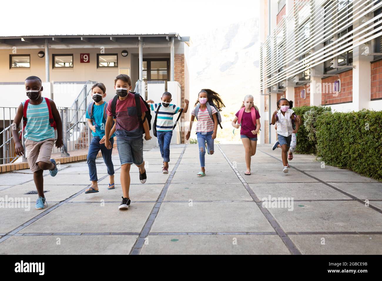 Group of diverse students wearing face masks running at elementary school Stock Photo