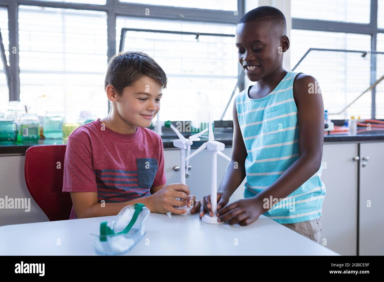 Caucasian boy and african american boy holding windmill models in science class at elementary school Stock Photo