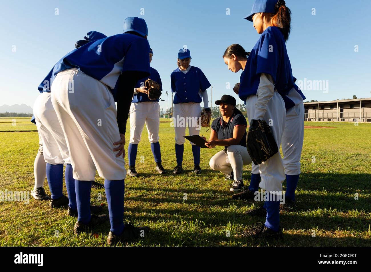 Diverse group of female baseball players standing in huddle around