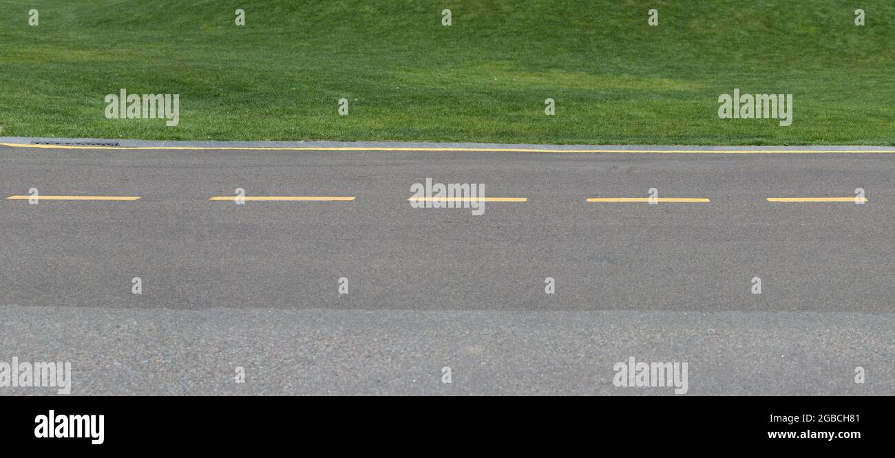 Panorama of a road with yellow markings along a green lawn. Stock Photo