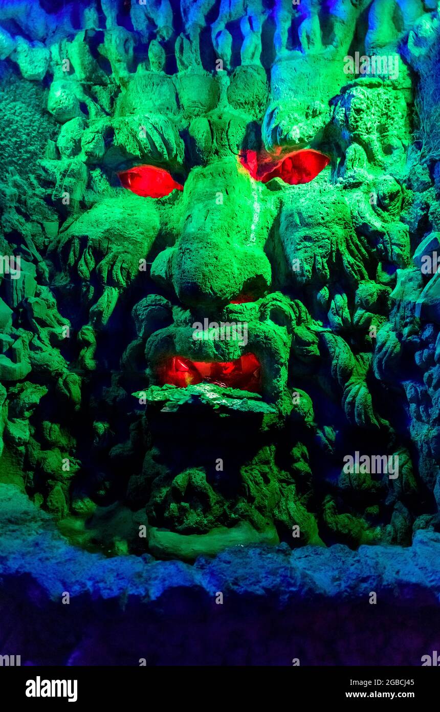 Grotesque green monsters head with red eyes and mouth. found in the grotto beneath the maze at Leeds Castle kent england Stock Photo