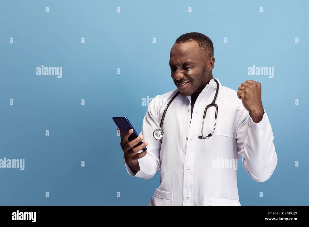 Young african doctor, therapeutic or medical advisor posing isolated on  blue studio back ground. Funny meme emotions. Concept of healthcare, care  Stock Photo - Alamy