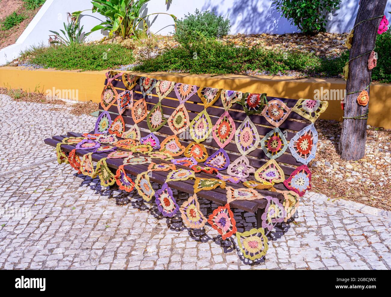 Crochet seat bench cover placed on a public bench São Bartolomeu do sul east Algarve Portugal Stock Photo
