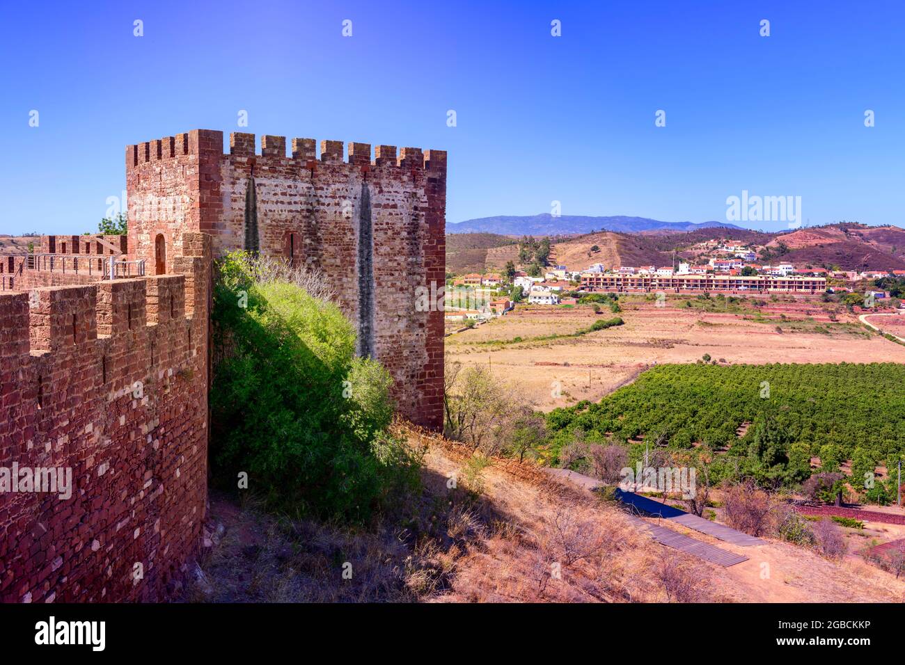 Square tower and battlements of Silves castle set against the surrounding hills, countryside and blue sky. Silves Algarve Portugal Stock Photo
