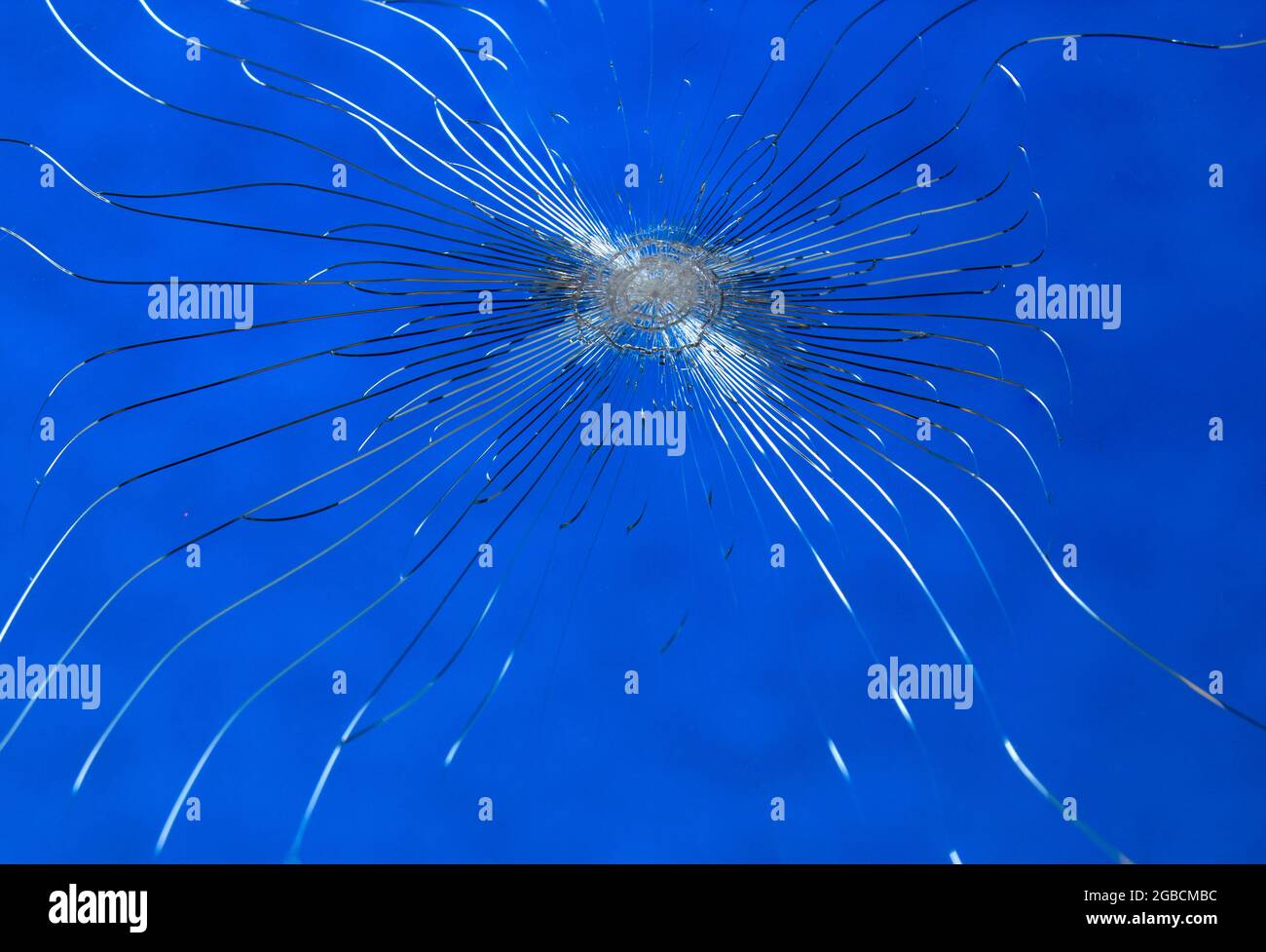 Cracked broken glass on a blue background. The window is broken by vandals, damaged by stone
