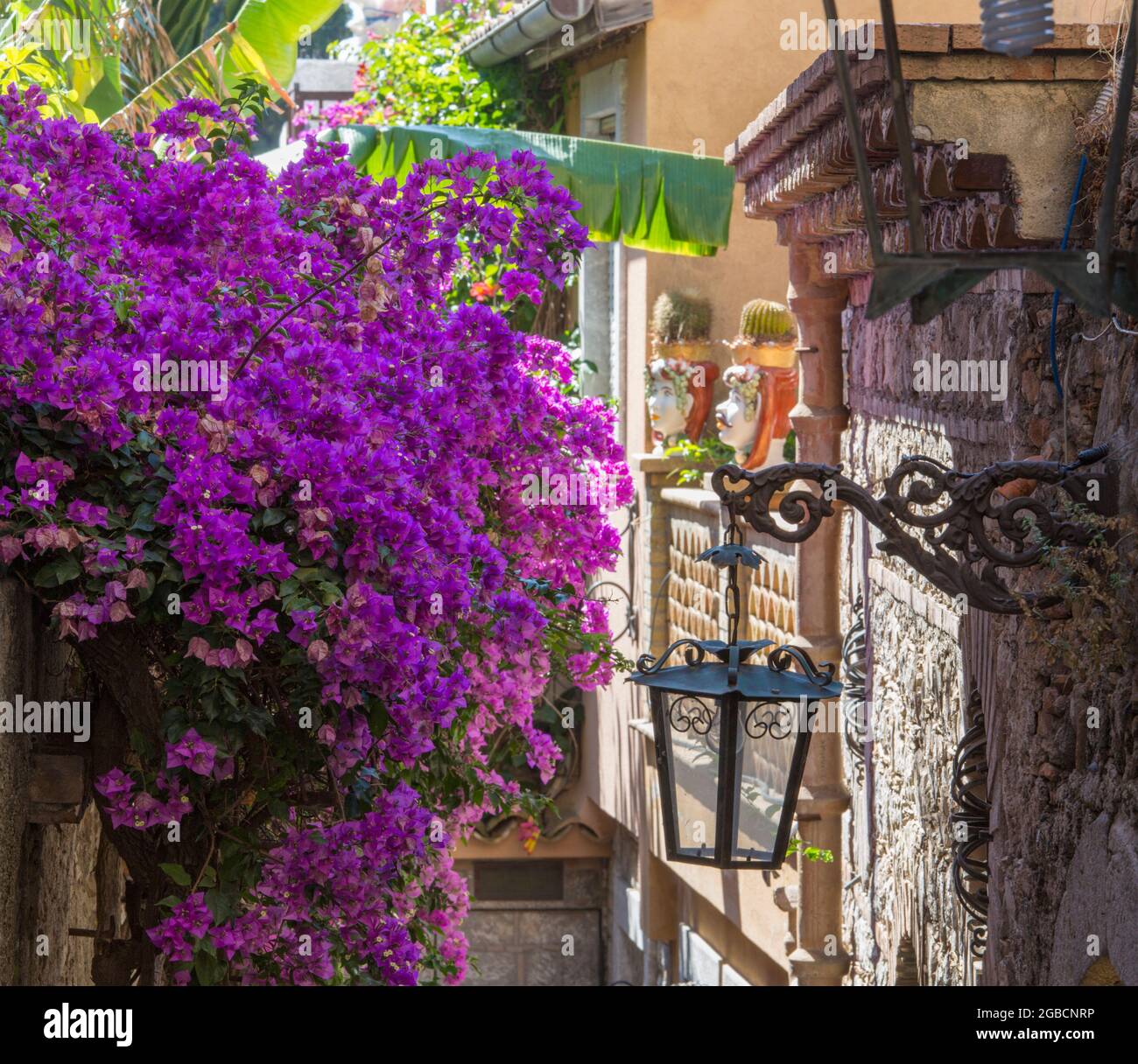 Taormina, Messina, Sicily, Italy. Typical flower-filled alley off Corso Umberto I, high stone wall draped in stunning pink bougainvillea. Stock Photo