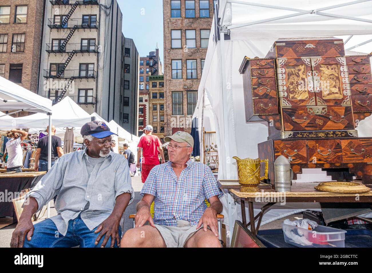 New York City,NY NYC,Manhattan Chelsea Flea Market,weekly open-air shopping marketplace antiques collectibles vendors booths stalls,Black men sitting Stock Photo