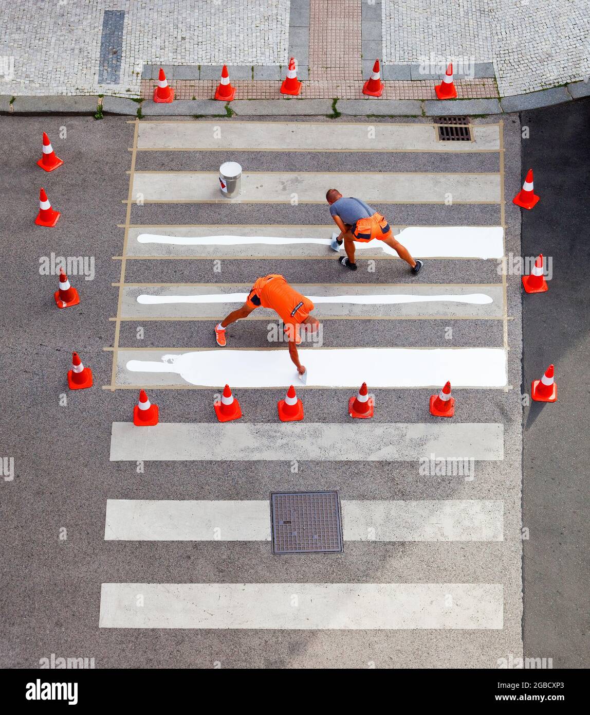 Workers painting crosswalk stripes with white colour. Stock Photo