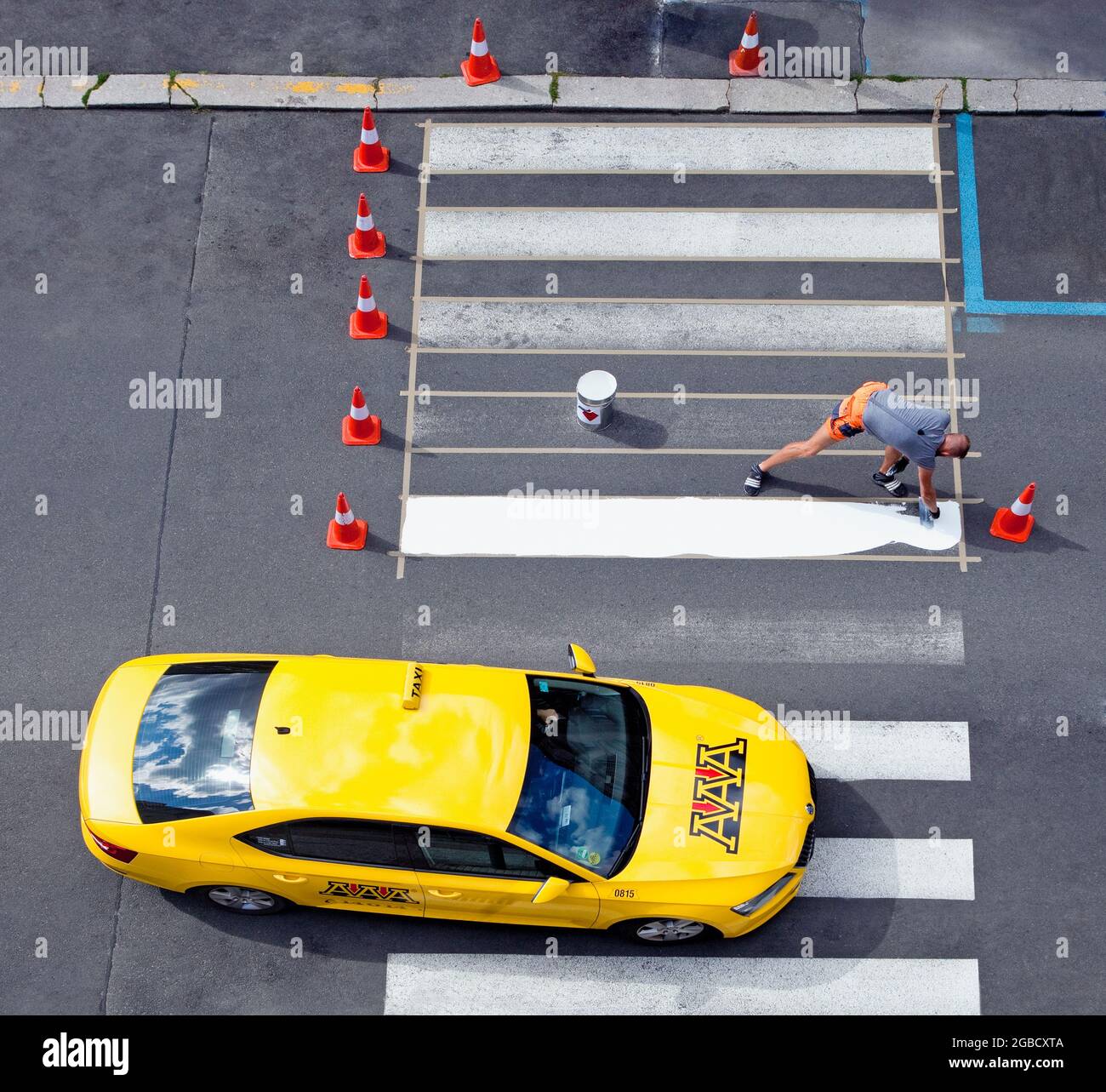 Workers painting crosswalk stripes with white colour. Stock Photo