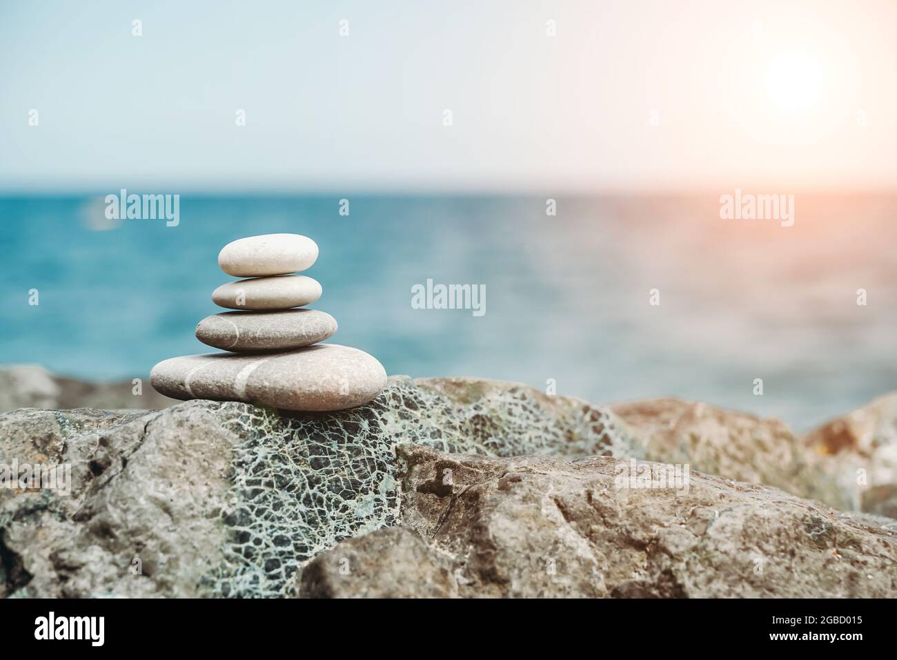 Zen stones are background. A pyramid of pebble stones against the background of the sky, sea and beach. Meditation, yoga, calming the mind and relaxation concept. High quality photo Stock Photo