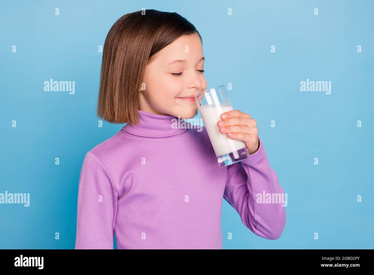 Photo portrait little girl drinking milk in the morning isolated pastel blue color background