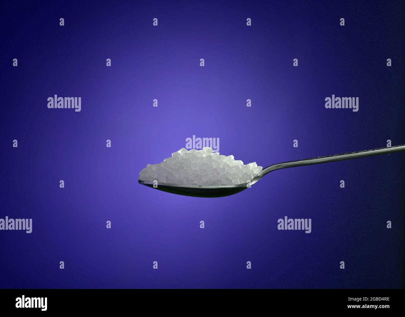 Sugar spoon on blue background Stock Photo