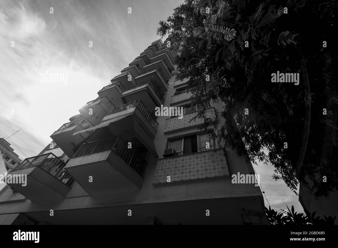 Grayscale shot of balconies in the apartment building against a cloudy sky Stock Photo