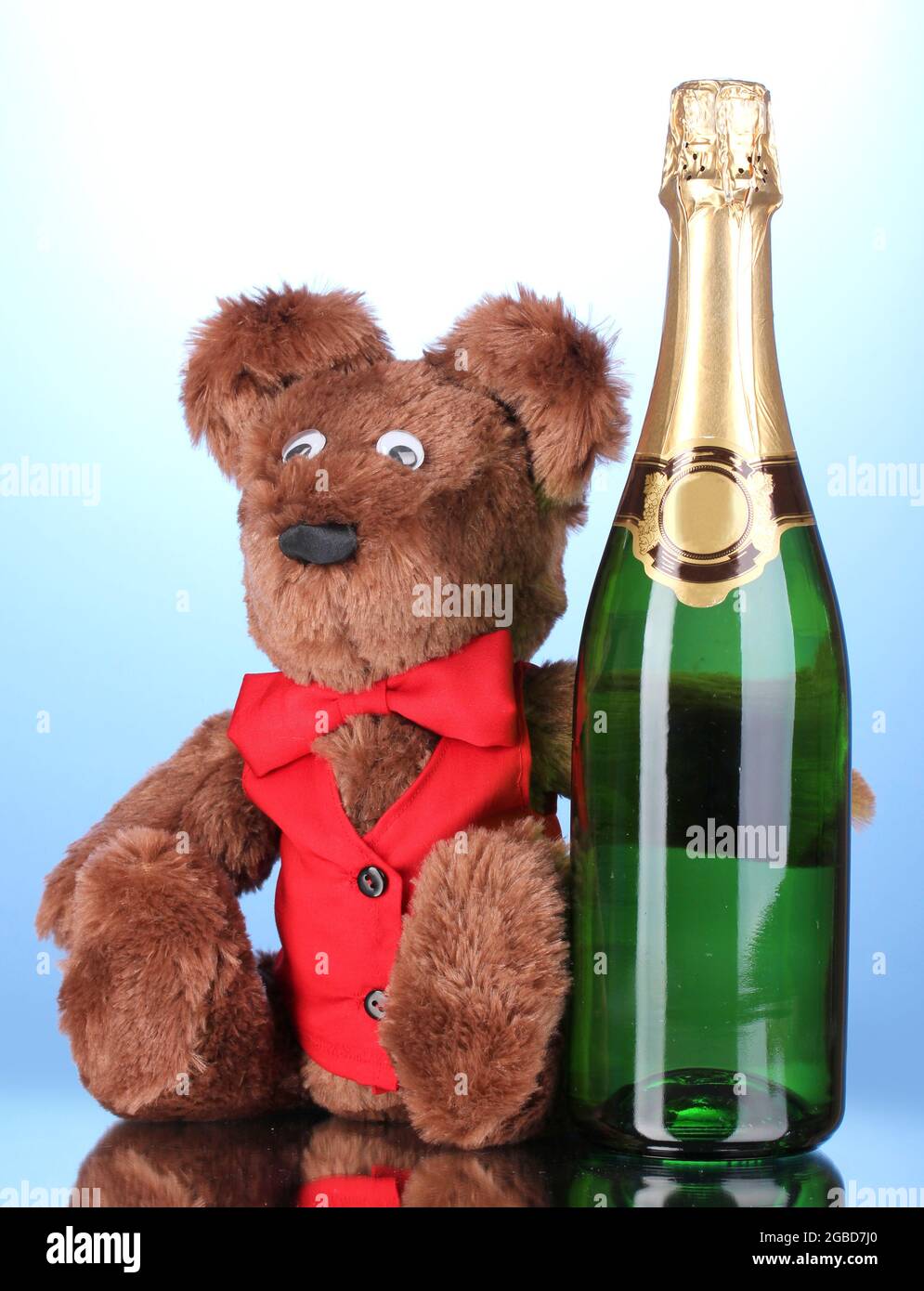 Toy bear and bottle of champagne on blue background Stock Photo - Alamy
