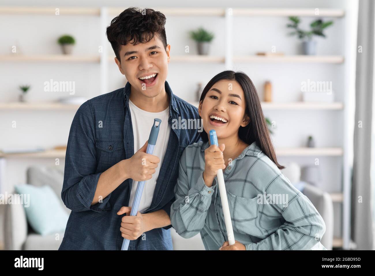 Closeup of positive asian lovers having fun while cleaning apartment Stock Photo