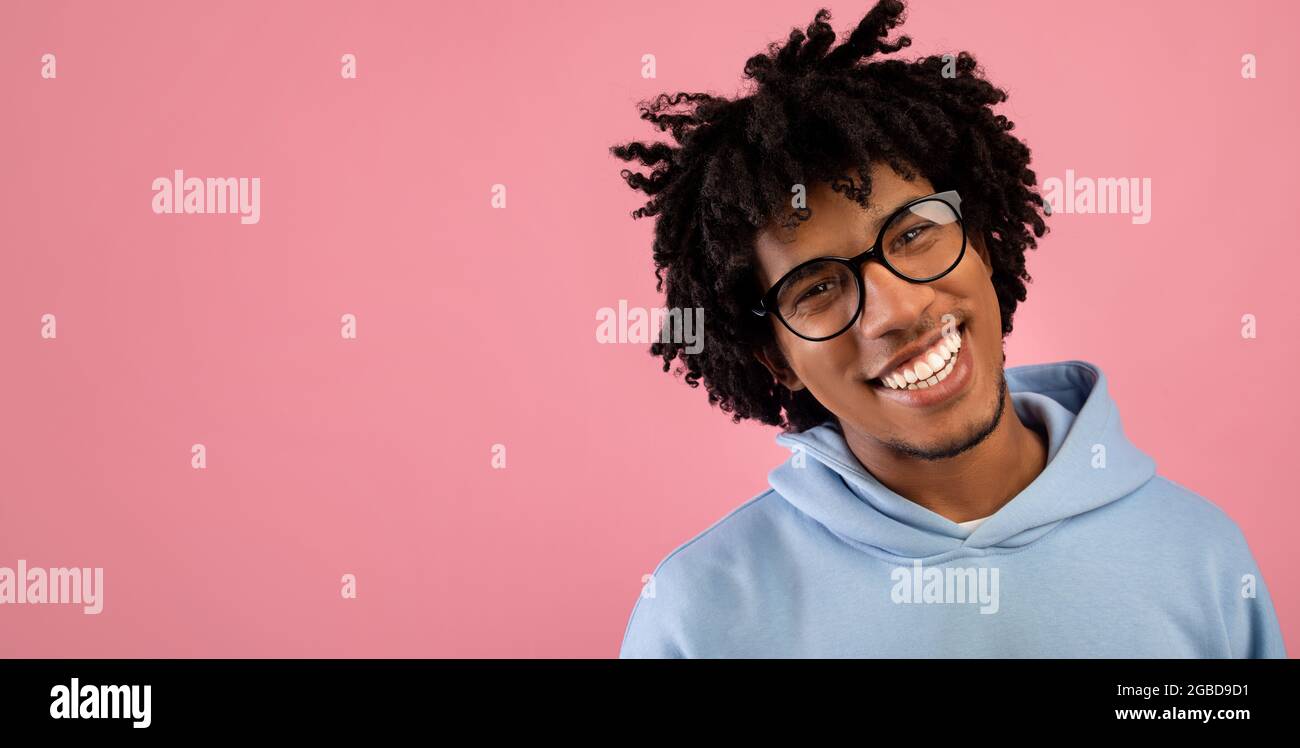 Portrait of handsome black teenager in casual clothes smiling and looking at camera over pink background, free space Stock Photo