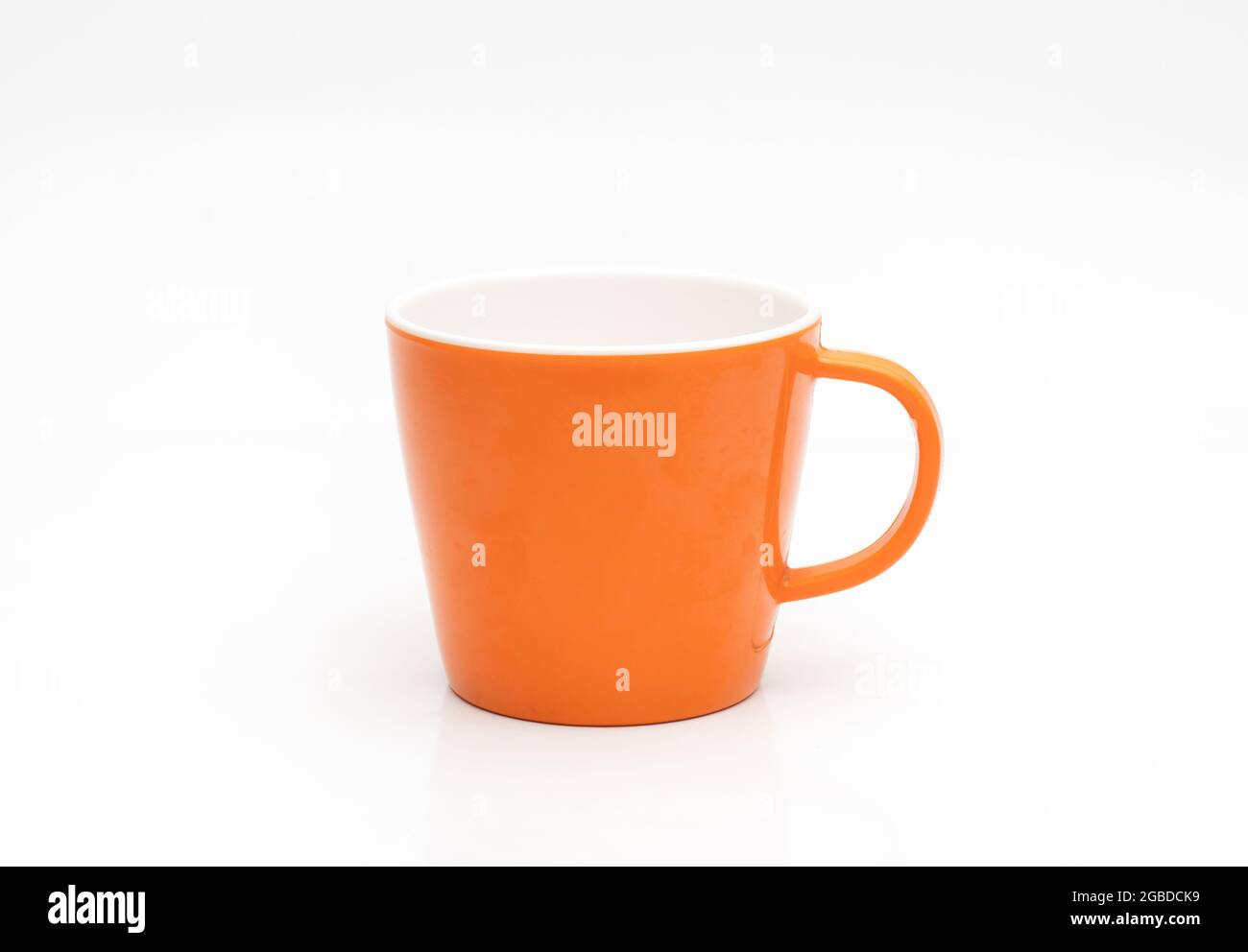 Orange color empty tea cup on isolated white background with reflection