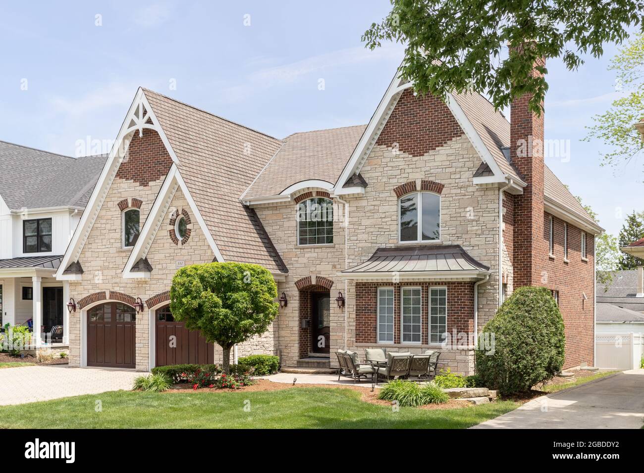 A full masonry home with a two car garage, front yard patio, brick paver driveway, and a mixture of brick and stone throughout the exterior. Stock Photo
