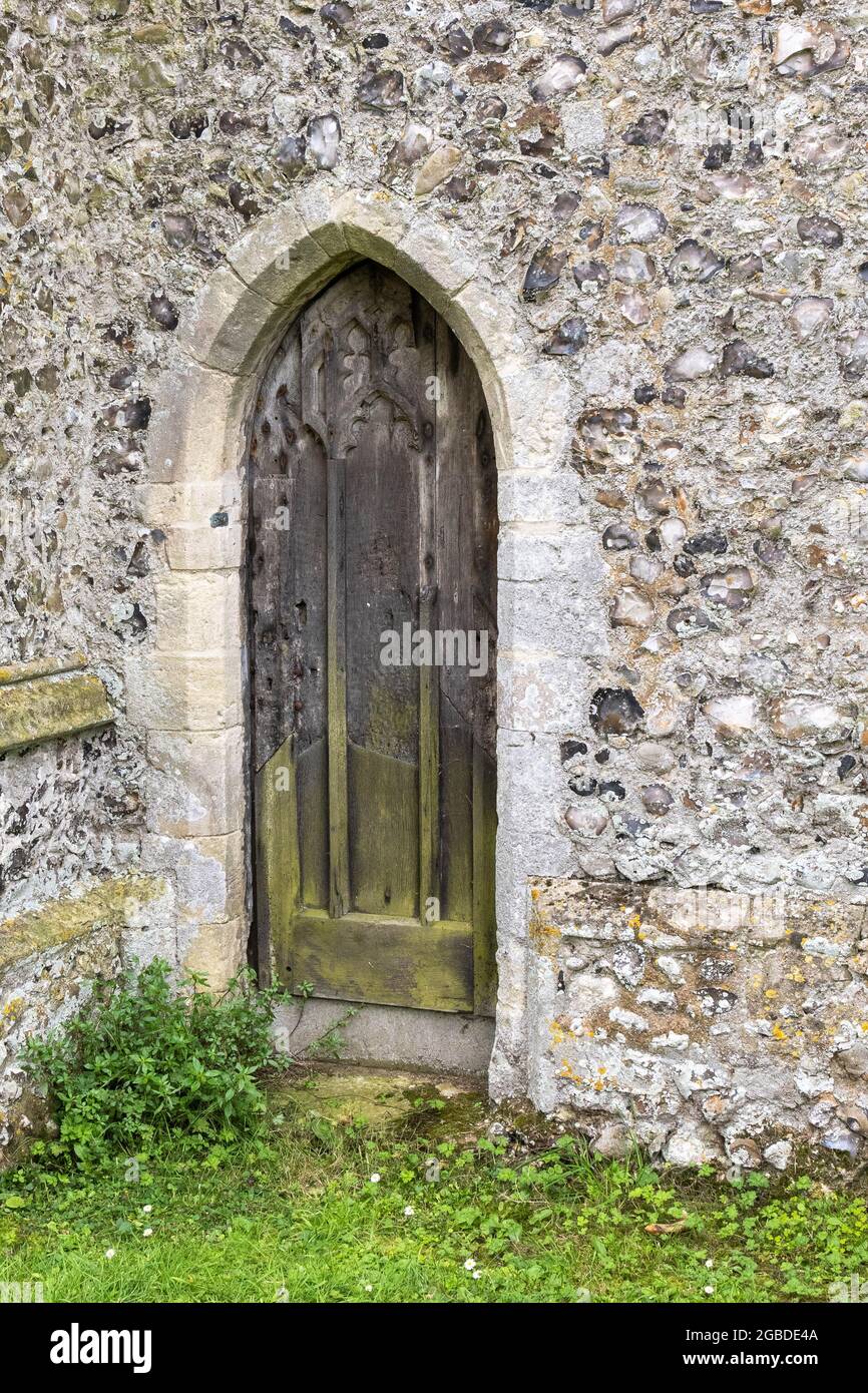 An old Oak Norfolk church arched side door set in a flint wall Stock