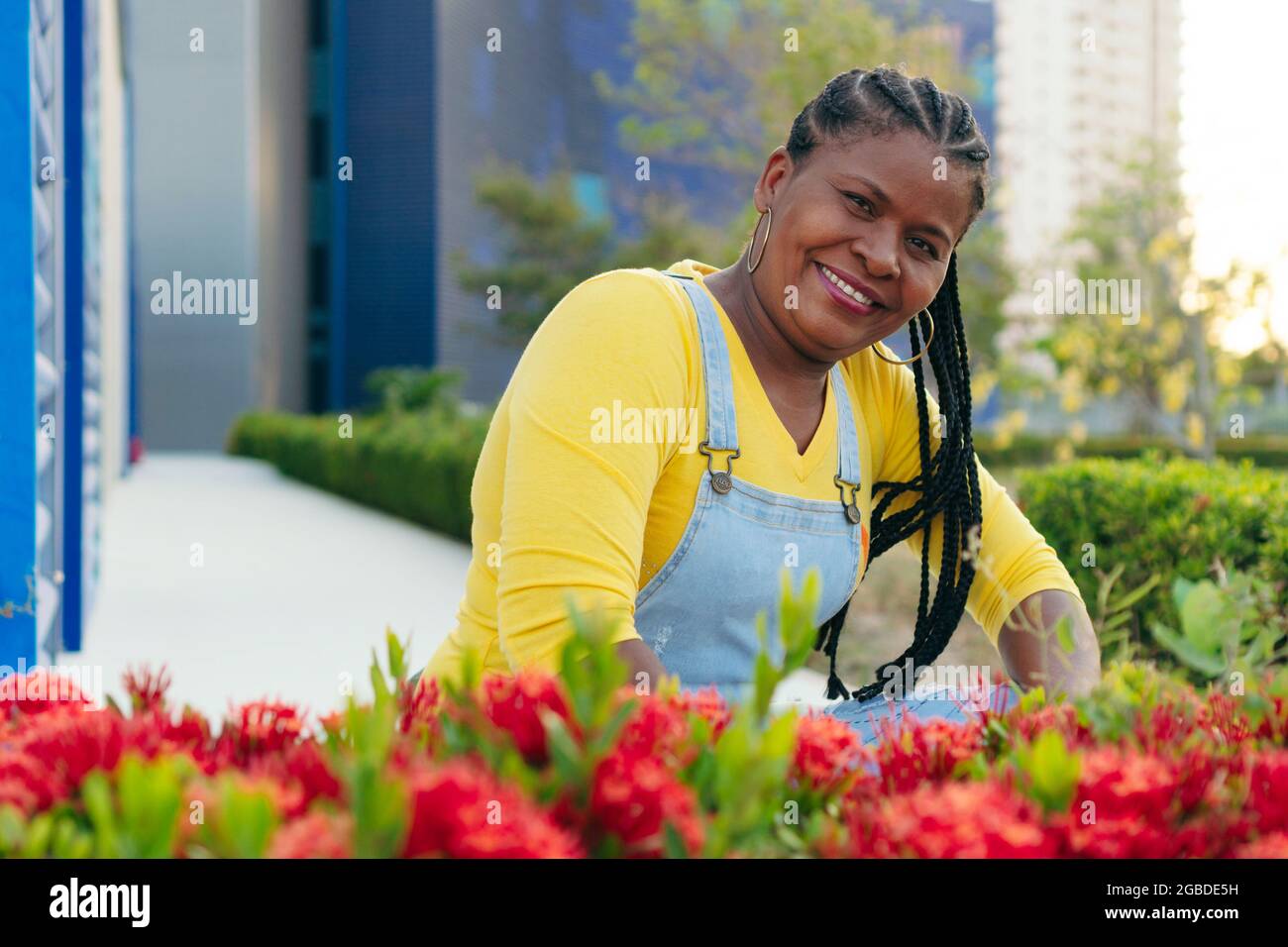Mature African woman posing near red flowers in the open air Stock Photo