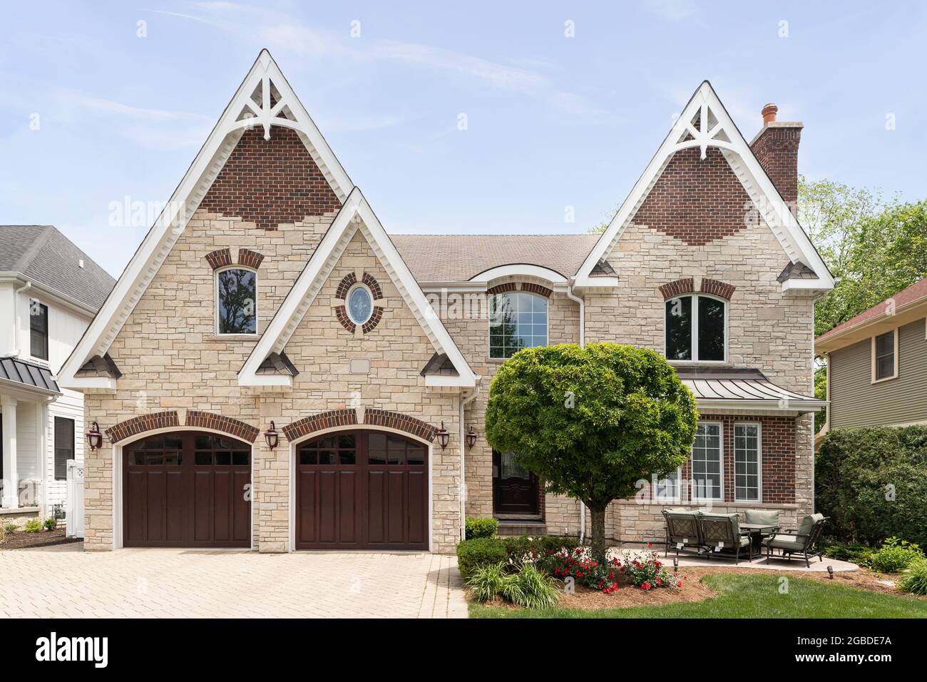 A full masonry home with a two car garage, front yard patio, brick paver driveway, and a mixture of brick and stone throughout the exterior. Stock Photo