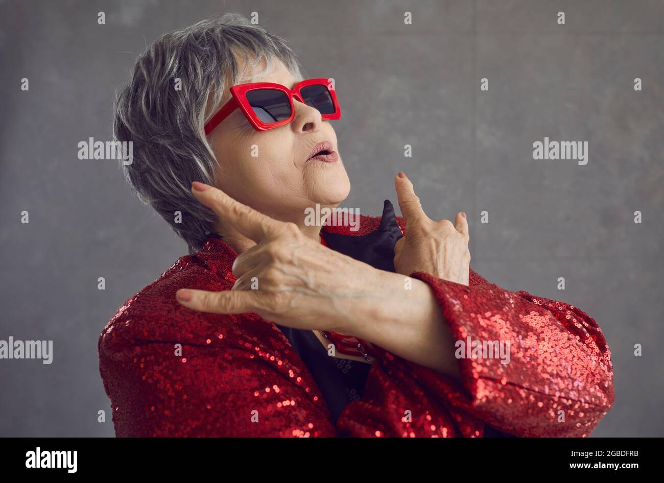 Senior fashionable woman star shows sign of horns with hands close up Stock Photo