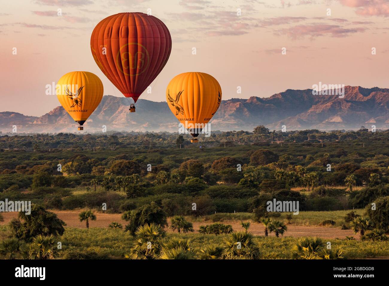 Several colored hot air balloons float over the fields of the Bagan temple site in Myanmar Stock Photo
