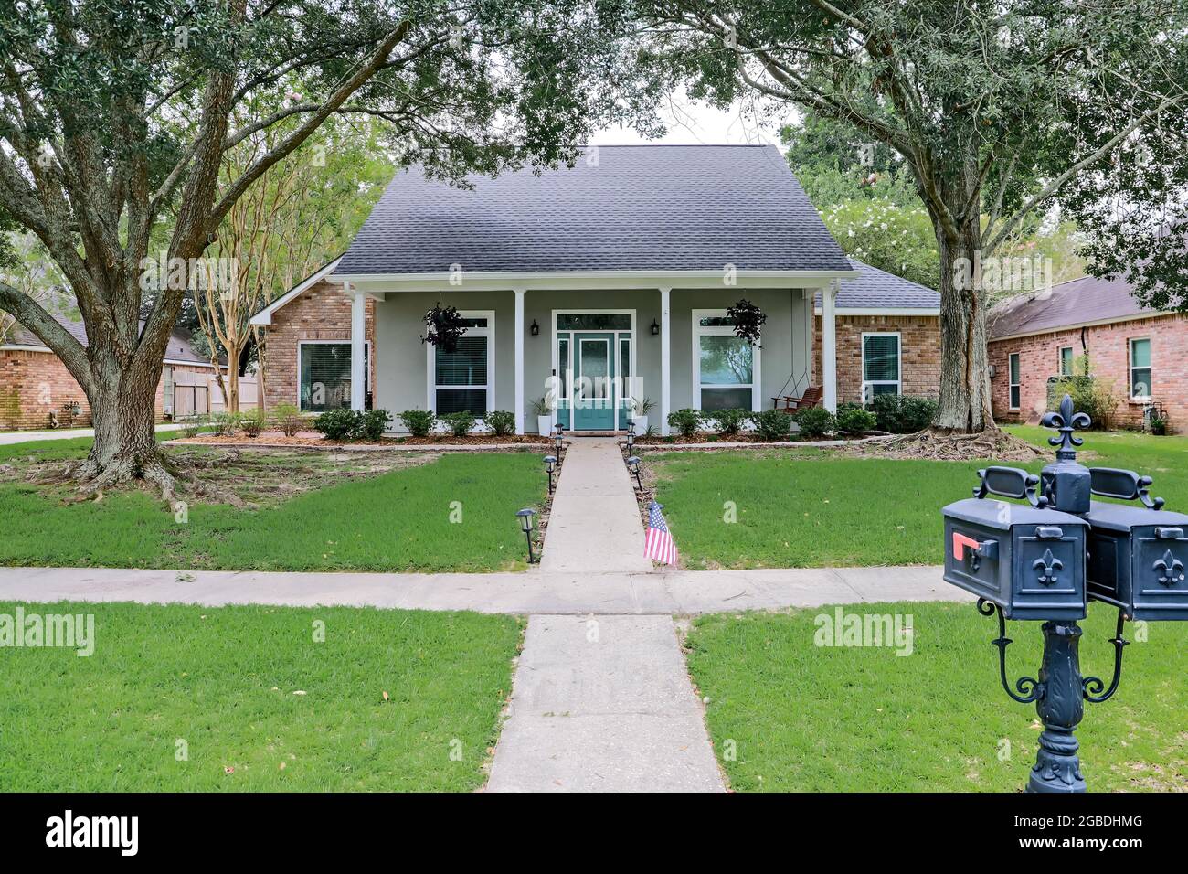 A front view of an Acadian renovated home with columns, sidewalks and a