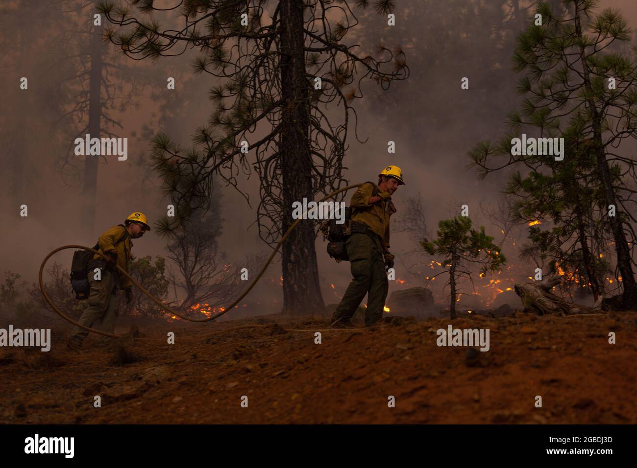 Fire crew members use a hose to control an area of the McFarland