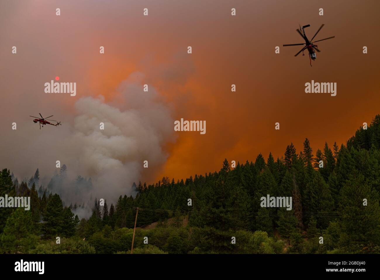Two helicopters circle and drop water on a section of the McFarland Wildfire neark Hayfork, CA