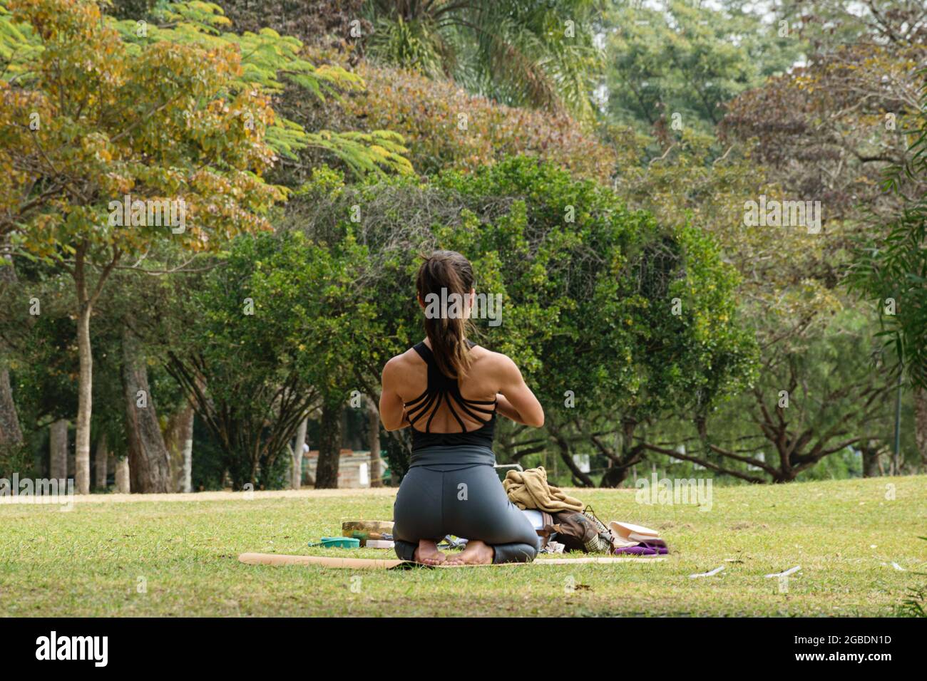 Sao Paulo, SP, Brazil, July 16 2021. 40-year-old woman with ripped back sitting on her feet in a yoga position in a public park. Stock Photo